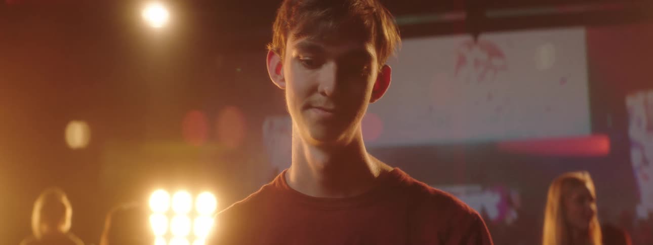 A teenager spins a drum stick in his hand while standing in front of other musicians