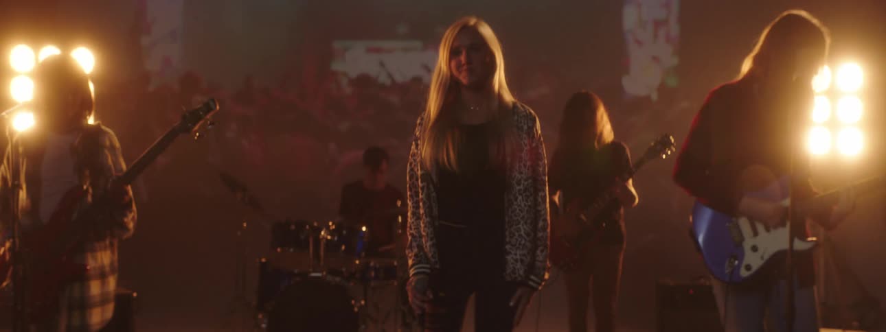 A teenager sways back and forth as her band plays during a performance