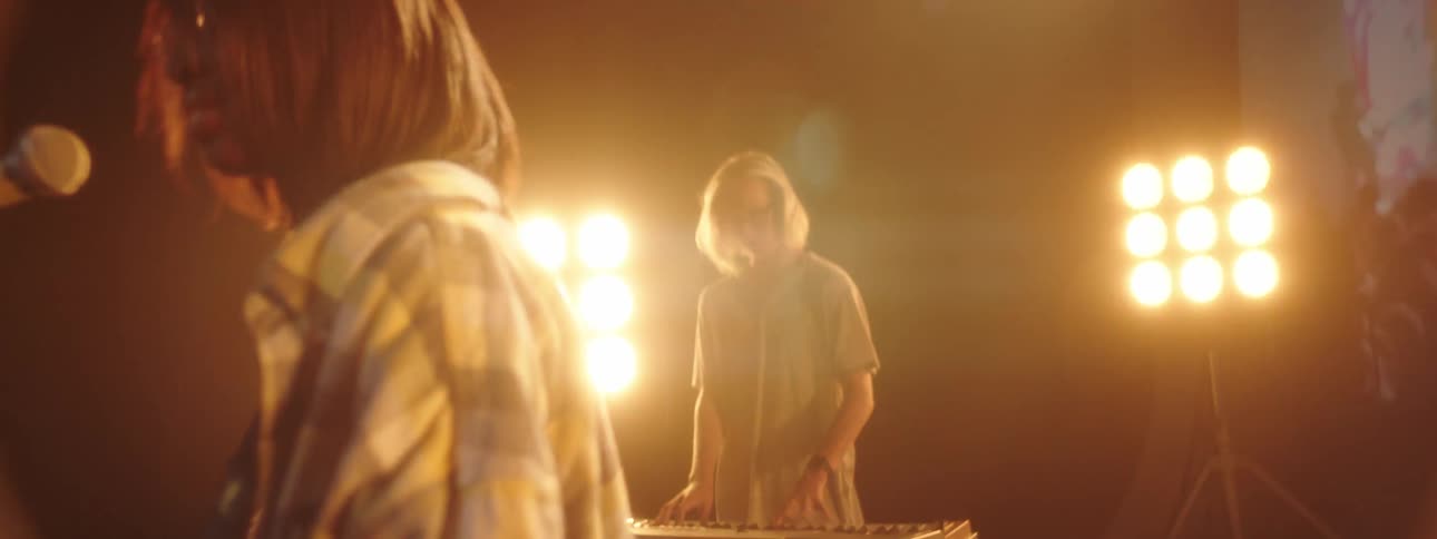 A band performs with a video of a crowd playing behind them