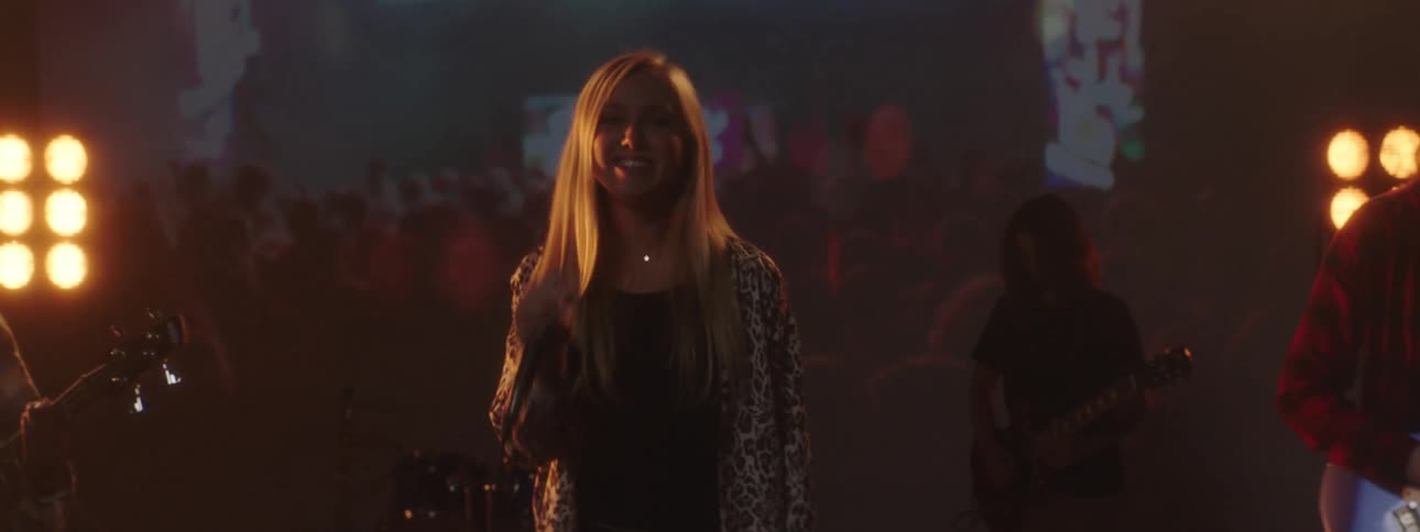 Blonde woman lead singer of a rock band performing on stage