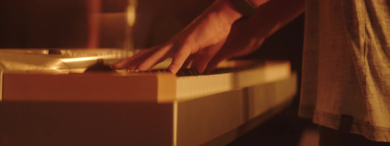Man wearing watch stands playing electric keyboard