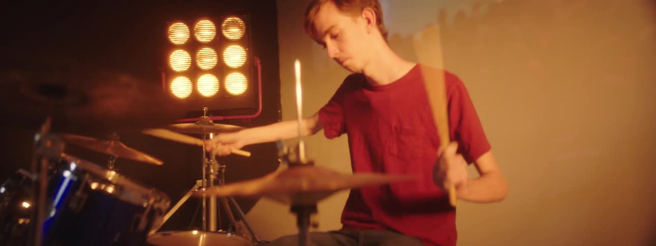 People playing instruments on a stage with spotlights a screen and a wall in the background