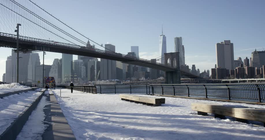A person walks towards a bridge leading to a city