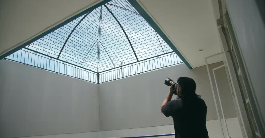 A photographer takes a photo of a domed skylight from below
