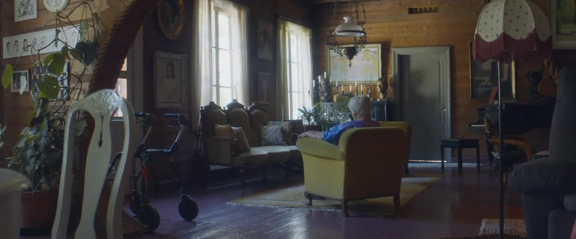 Elderly woman sitting on a chair in the living room of a cozy home