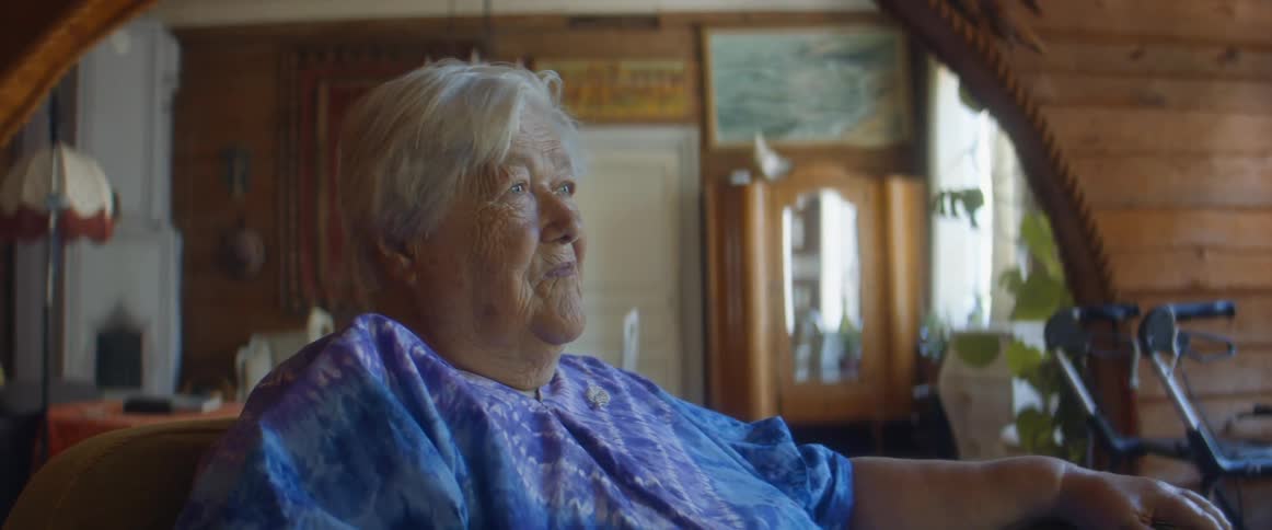 An elderly woman sits in her living room while lost in thought during the day