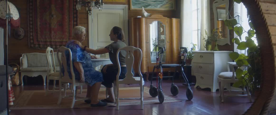 A woman rubs her moms shoulder as they sit at their dining room table