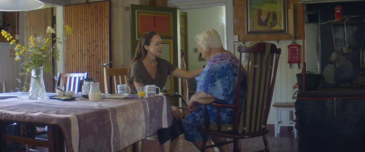 Young woman taking car of an elderly lady sitting on the dining table at home