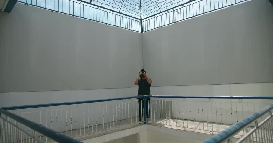 A photographer raises his camera to take a photograph of a skylight in a large stairwell
