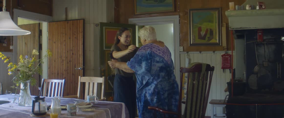 Young woman greets an elderly lady with a hug in the dining room at home