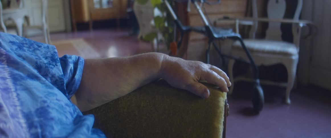 An elderly person sits in their home chair quietly