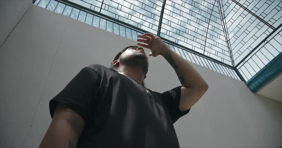 Man stands shading his eyes with his hand as he looks up at glass enclosed ceiling