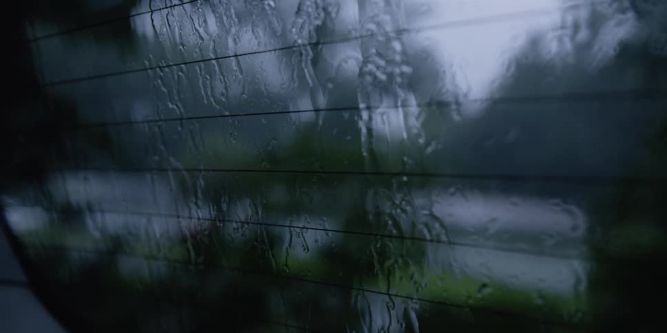 Rain runs down the back window of a vehicle