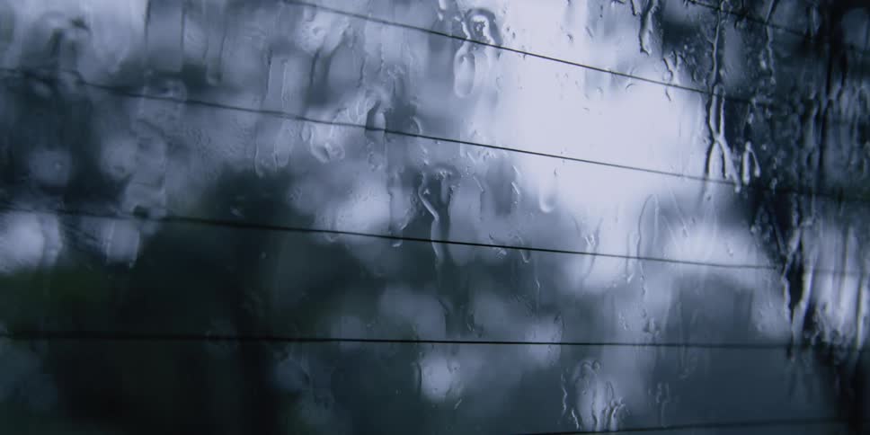 Rain falls on a windshield shown from inside a vehicle