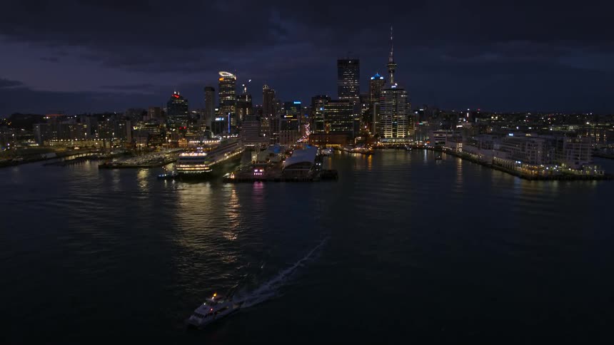 A speedboat moves away from a city skyline as it sails through the ocean