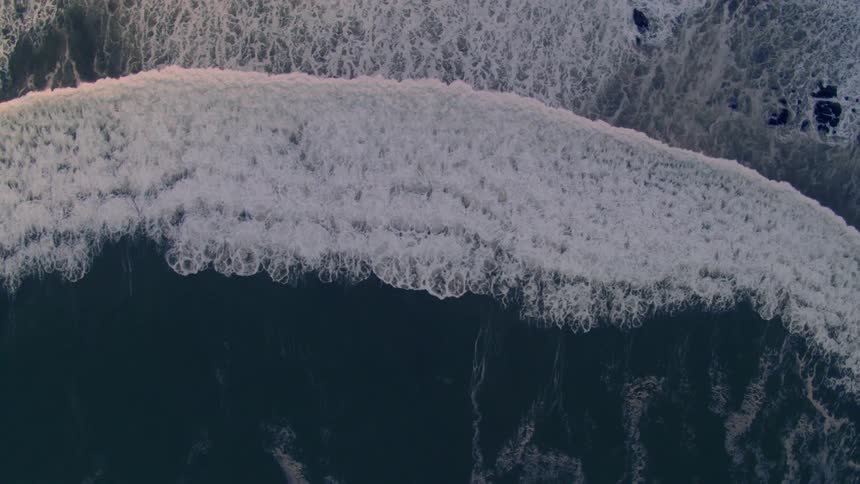 An aerial view of a wave crashing in the ocean