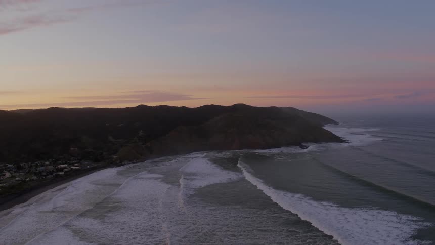 Ocean waves crash onto the shore of a coastal neighborhood beach