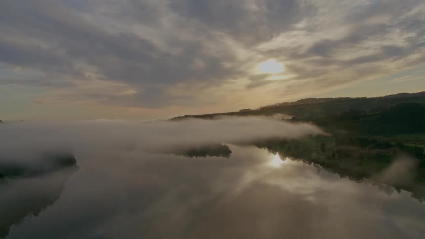 An aerial view of a lake with the sun in the distance