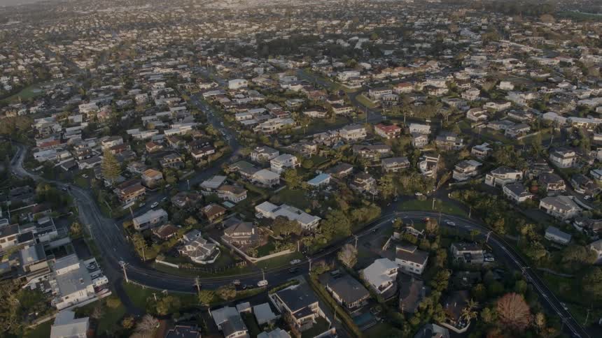 Traffic follows winding highway through middle of neighborhood of low rise buildings near waterfront