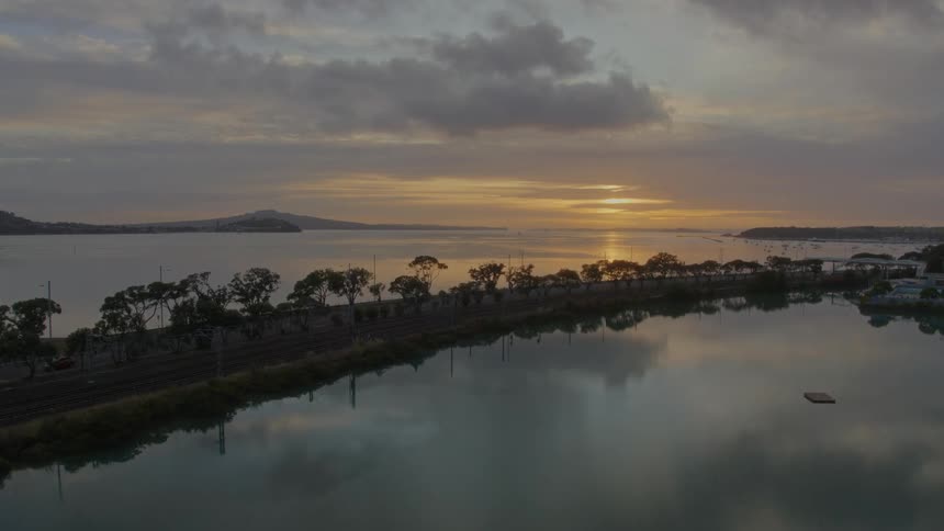 A peninsula stretches across the water leading to a small structure