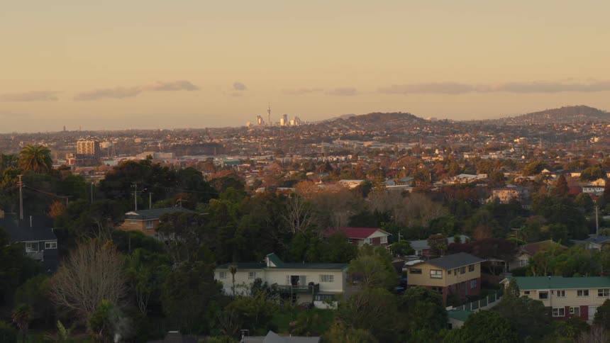 Houses and trees in a city neighborhood with mountains in the distance