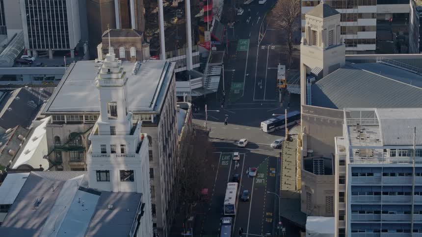 Buses and cars turn at a city street intersection on a sunny day