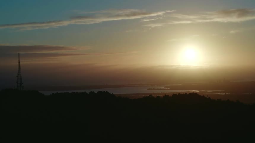 An aerial view of a river with sun setting in the distance