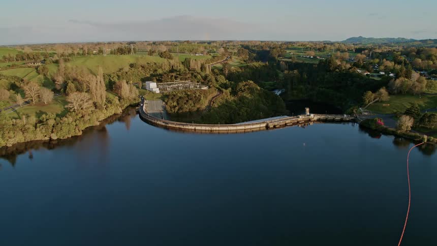 A landscape with a dam and a road with the sky and clouds in the background