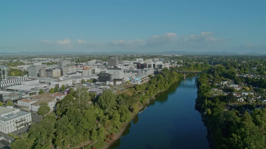 A city skyline with a river and a bridge with the sky and clouds in the background