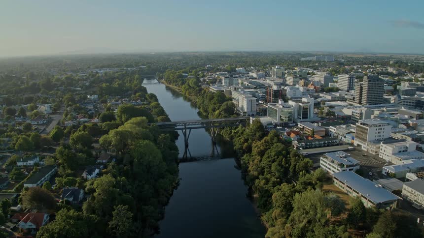 A city skyline with a river and a bridge with the sky and clouds in the background