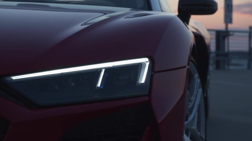 A red sports car with chrome trimmed headlights sits in a parking lot