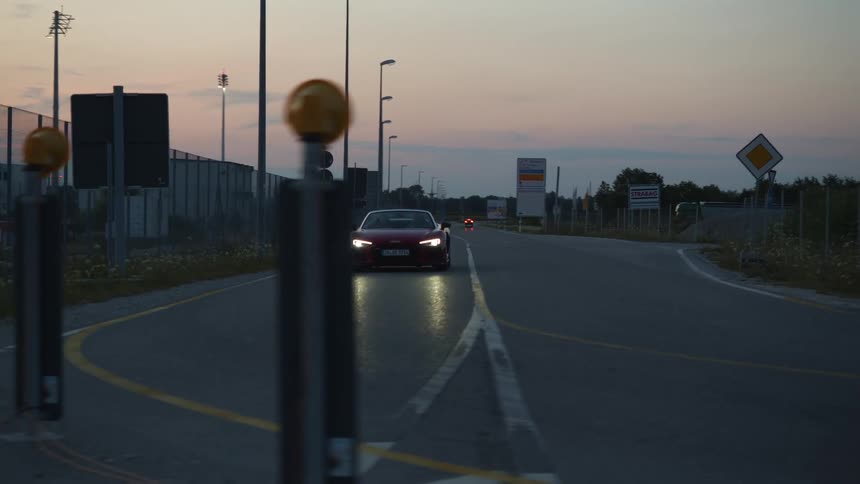 A red convertible drives around a curve in the road