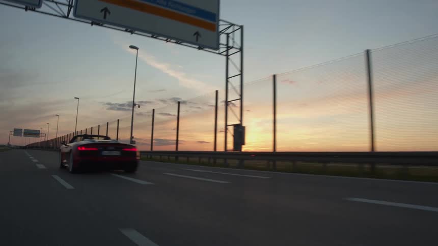 A black convertible speeds in the right lane of an empty highway