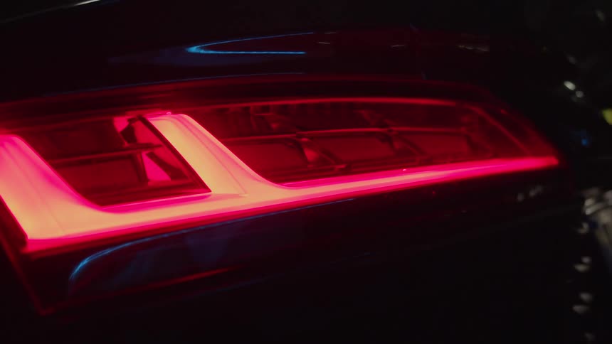 A vehicle taillights with lights reflecting off the body