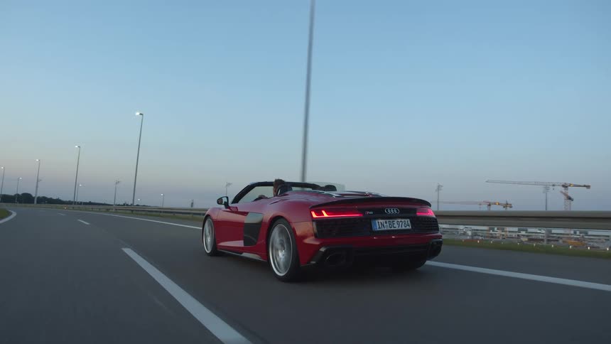 A man drives a red convertible down a highway with the top down