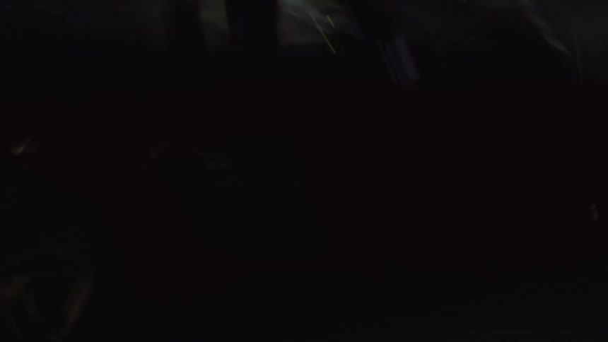 A red car travels downtown at night
