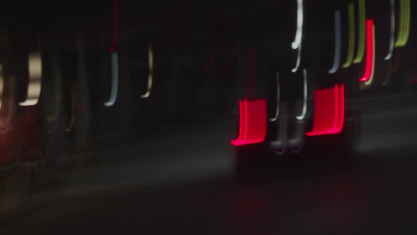 A vehicle driving on a city road would lights in the background