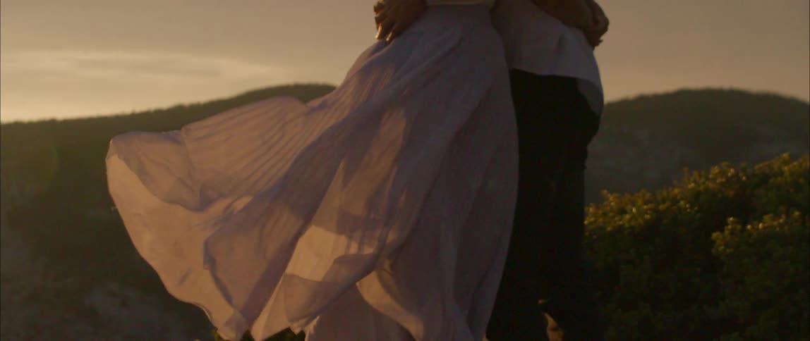 A couple hug on a hill at sunrise