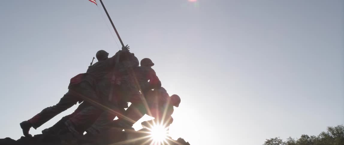 A statue is shown with the sun behind it