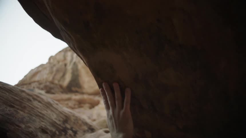 Man brushes his hand over the wall of a canyon at morning