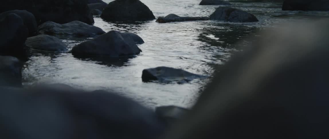 Water moving and reflecting sunlight in a creek filled with rocks
