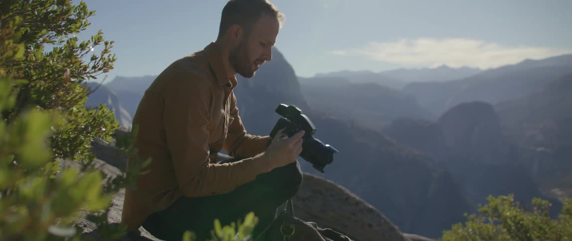 A photographer changing film in a camera outdoors