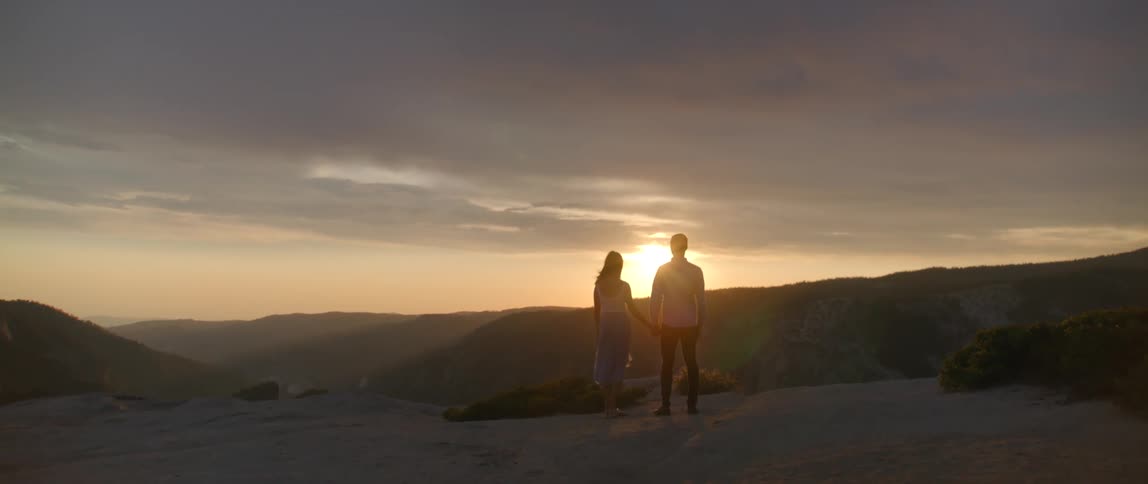 Two people standing together at sunset