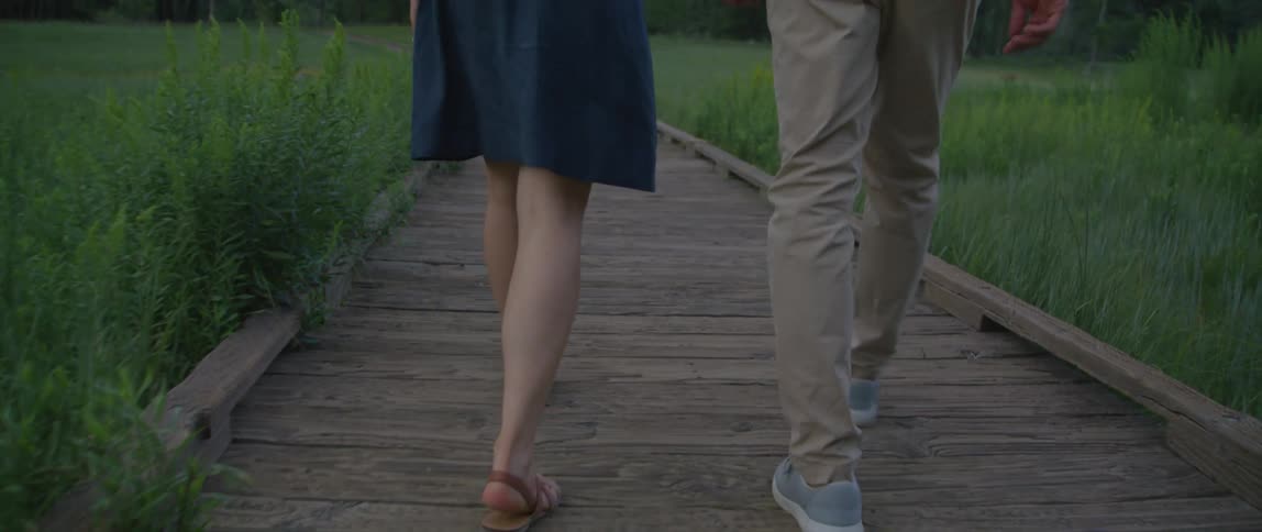 A couple hike on a path towards a mountain range
