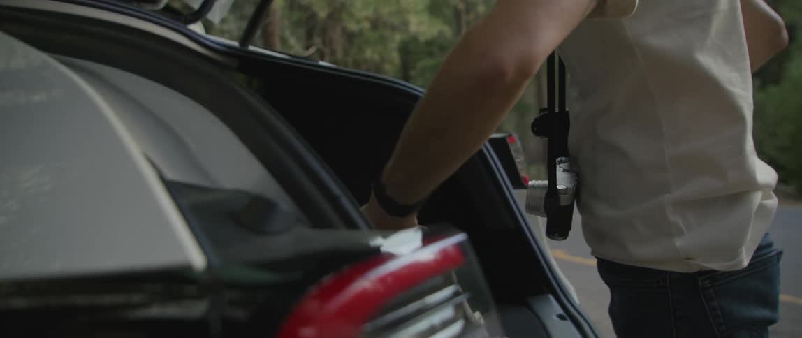 A man is gathering camera equipment out of the trunk of his car