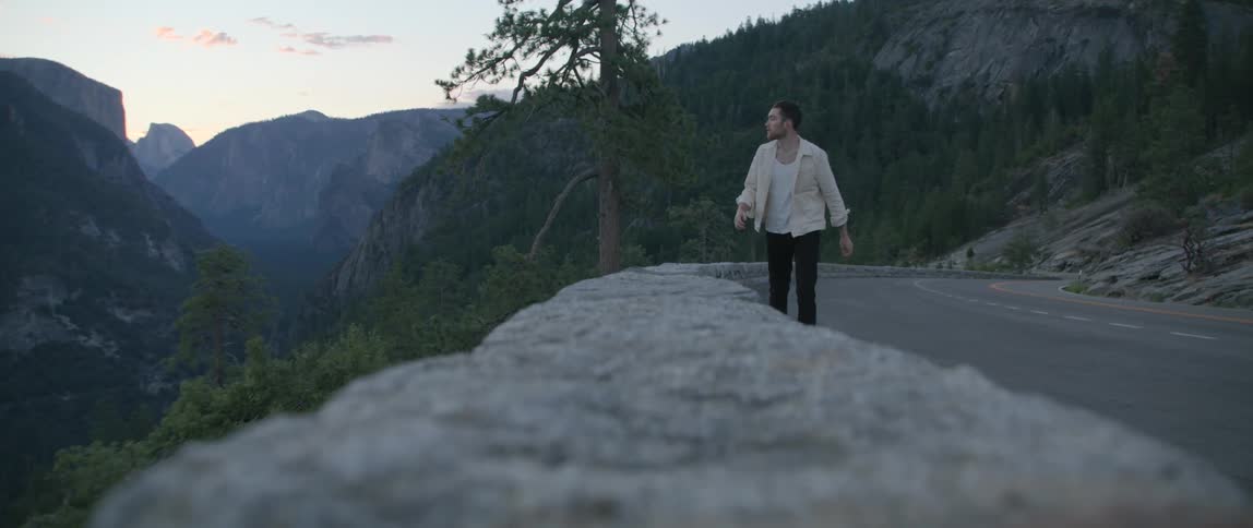A man is walking on the side of the road