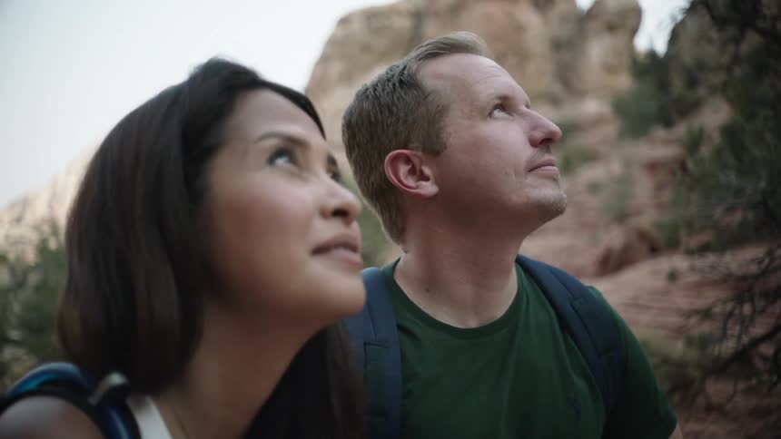 A man and woman are looking up at a mountain