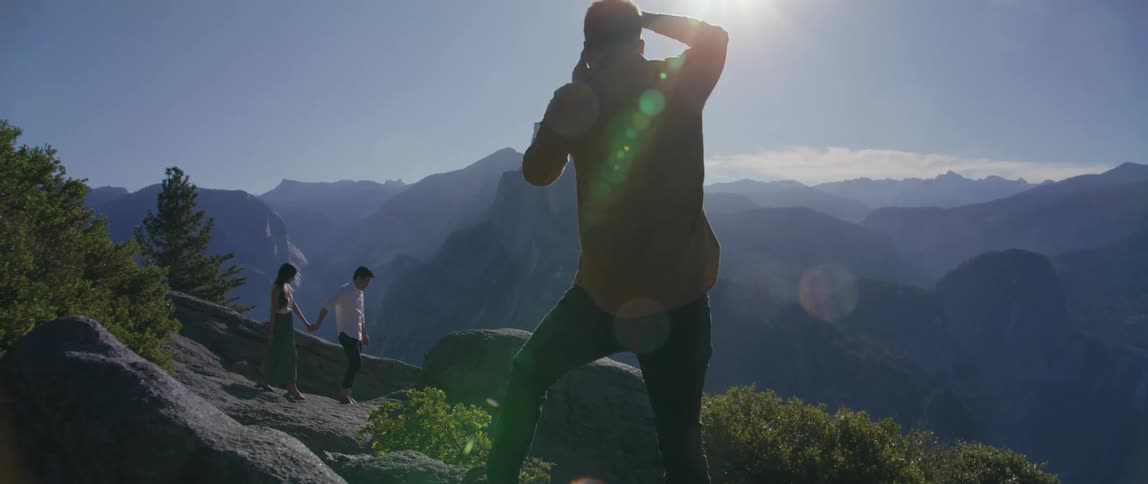 A man taking photos of two people outdoors