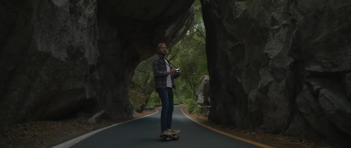 Man rides a skateboard on a road on a small canyon on a park