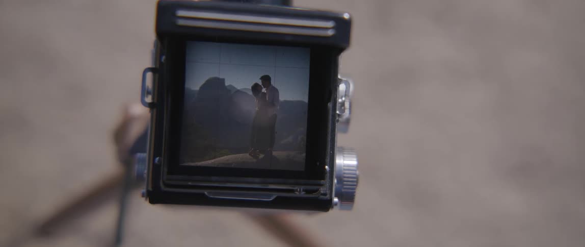 Video camera showing a recording of a man and woman kissing near the mountains